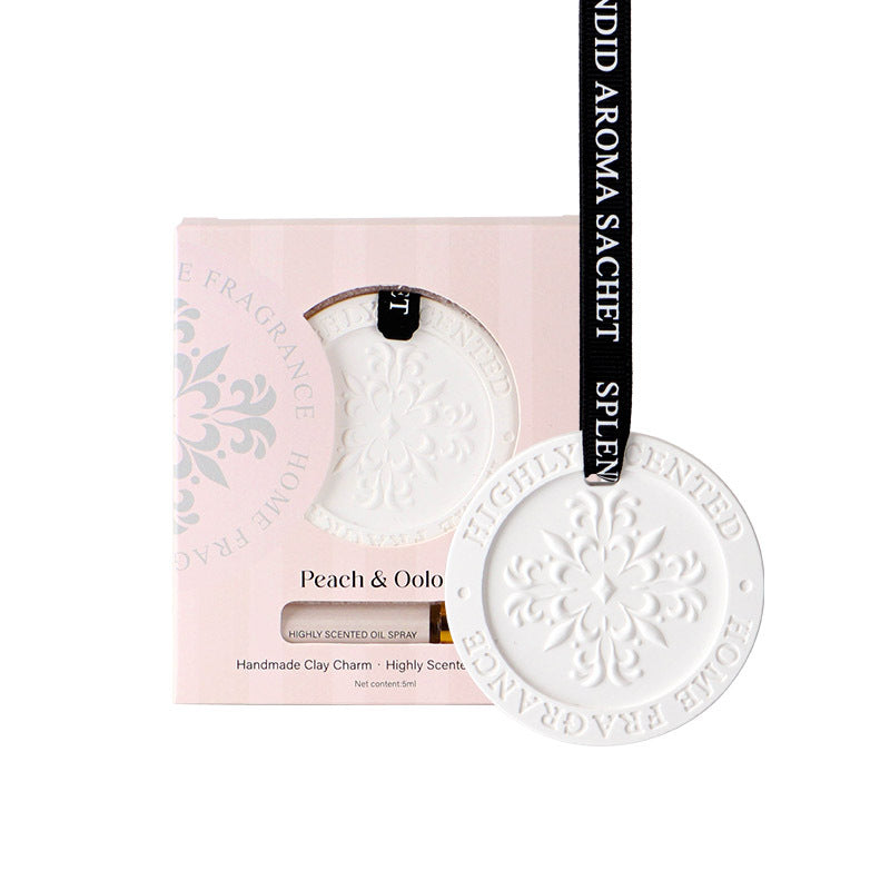 White ceramic charm with 'Peach & Oolo' branding on a pink packaging background