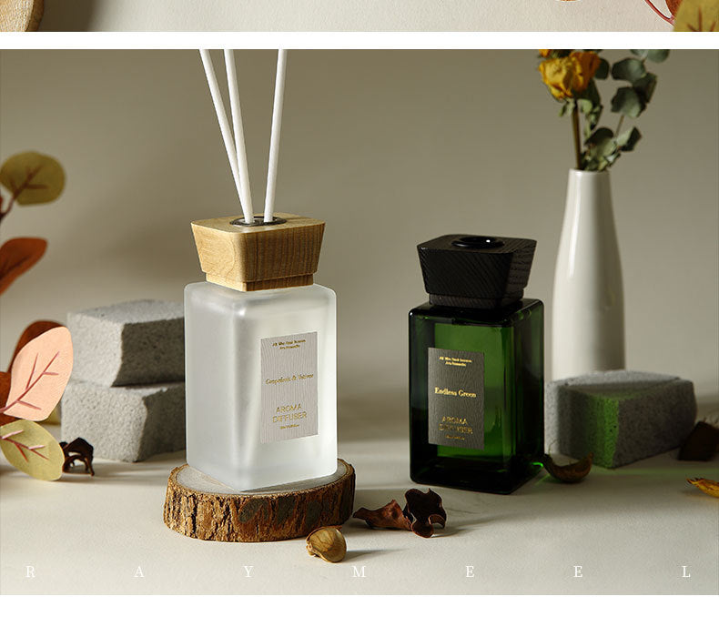 A diffuser with wooden base and white sticks, surrounded by decorative elements on a neutral background.