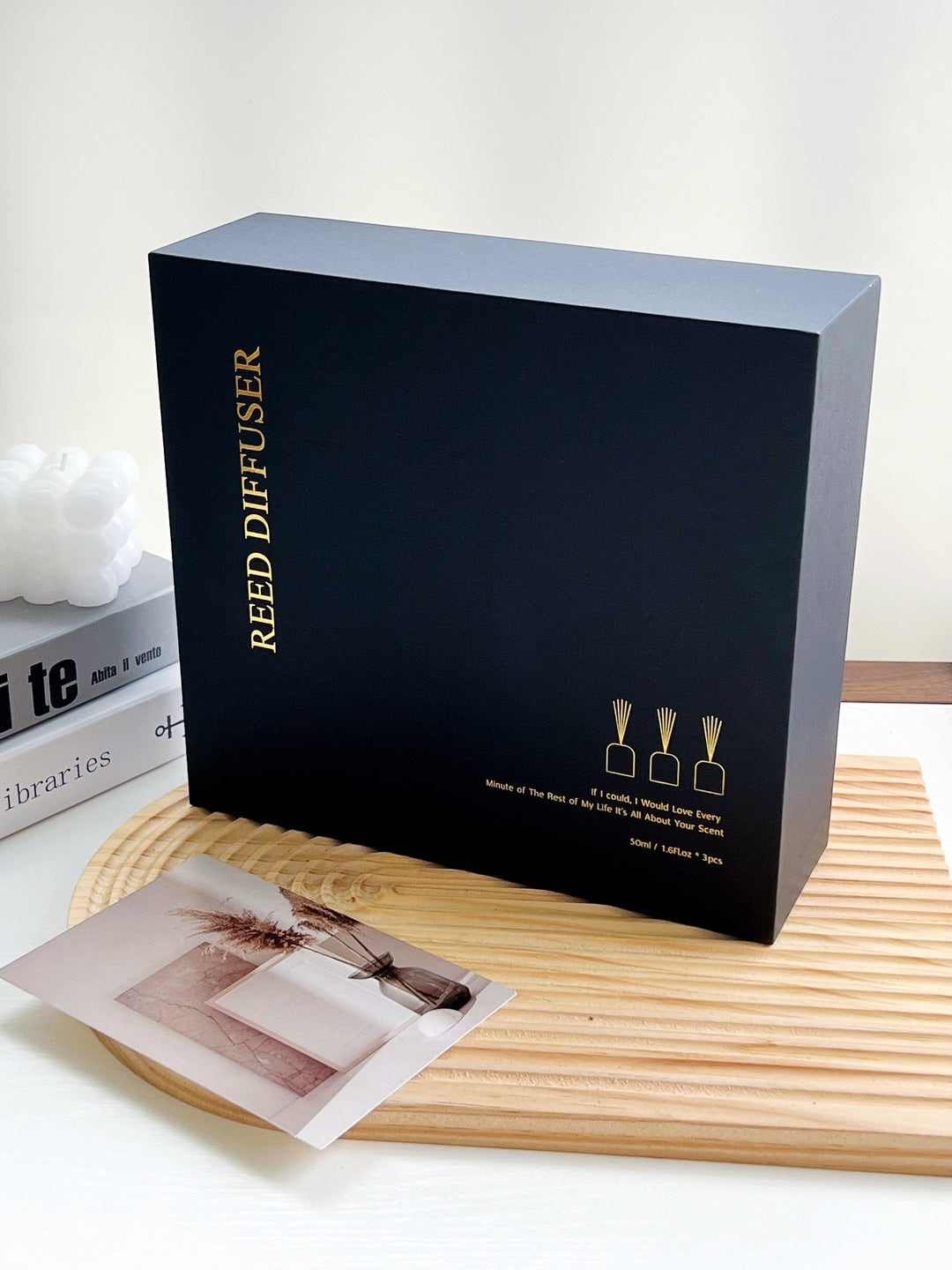 Black box labeled 'Reed Diffuser' on a wooden surface with a white background