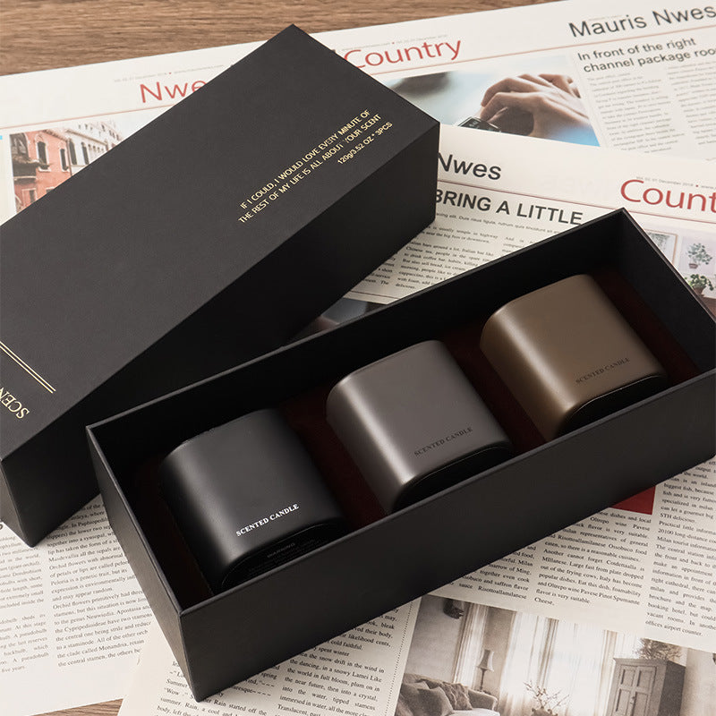Three cylindrical containers in a black box on top of a newspaper.