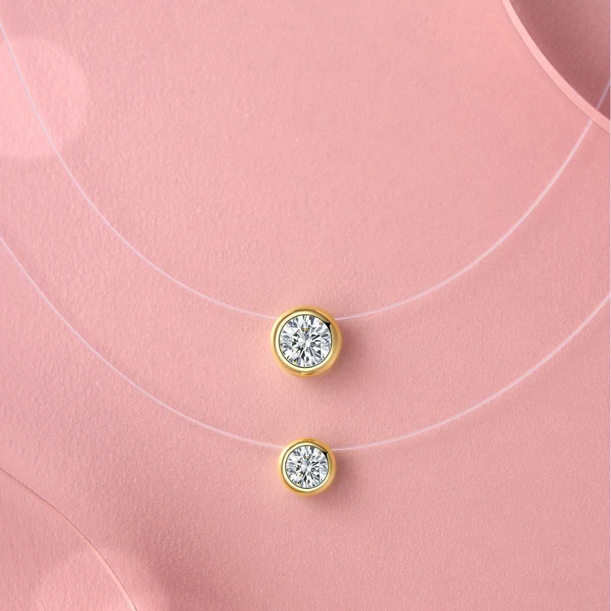 Gold earrings with clear gemstones on a pink background