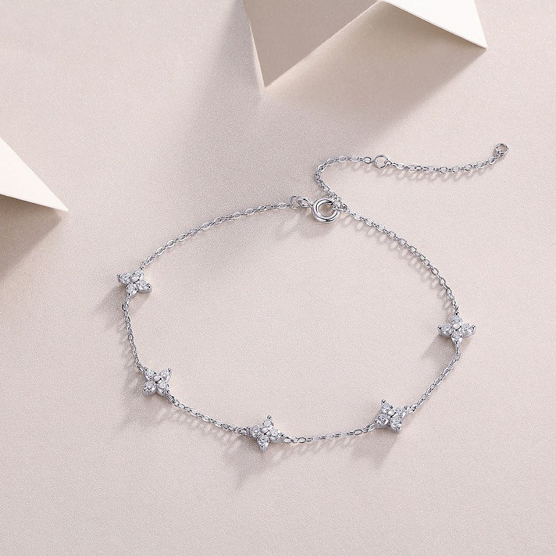 Silver bracelet with star-shaped charms on a light pink background