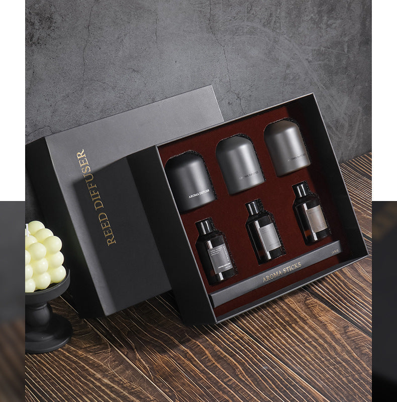 Set of Reed Diffuser bottles in a black box on a wooden surface with a gray background