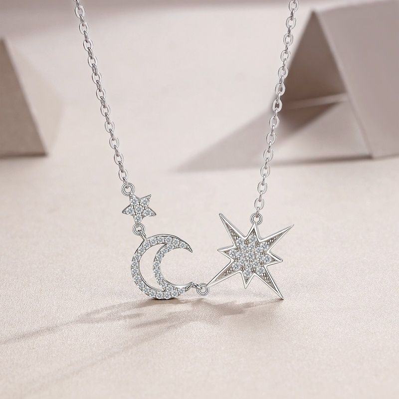 Silver necklace with star and moon pendants on a light background