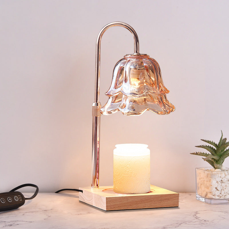 Decorative table lamp with glass shade and wooden base on a marble surface.