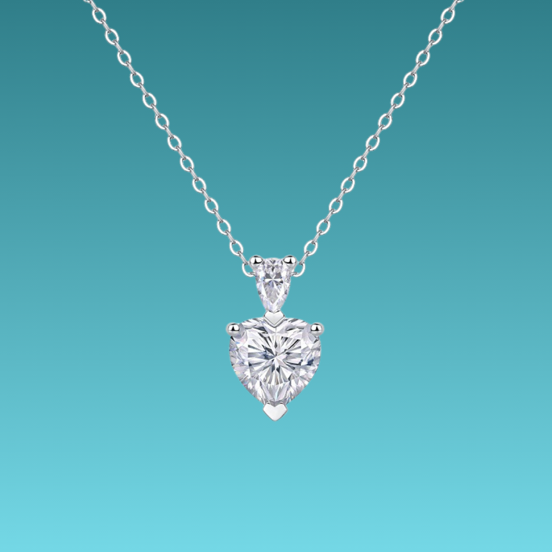 Heart-shaped diamond pendant on a chain against a teal background