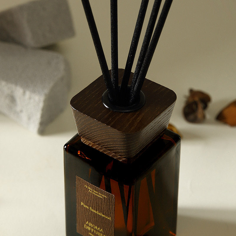 Aroma diffuser with wooden base and black sticks on a neutral background