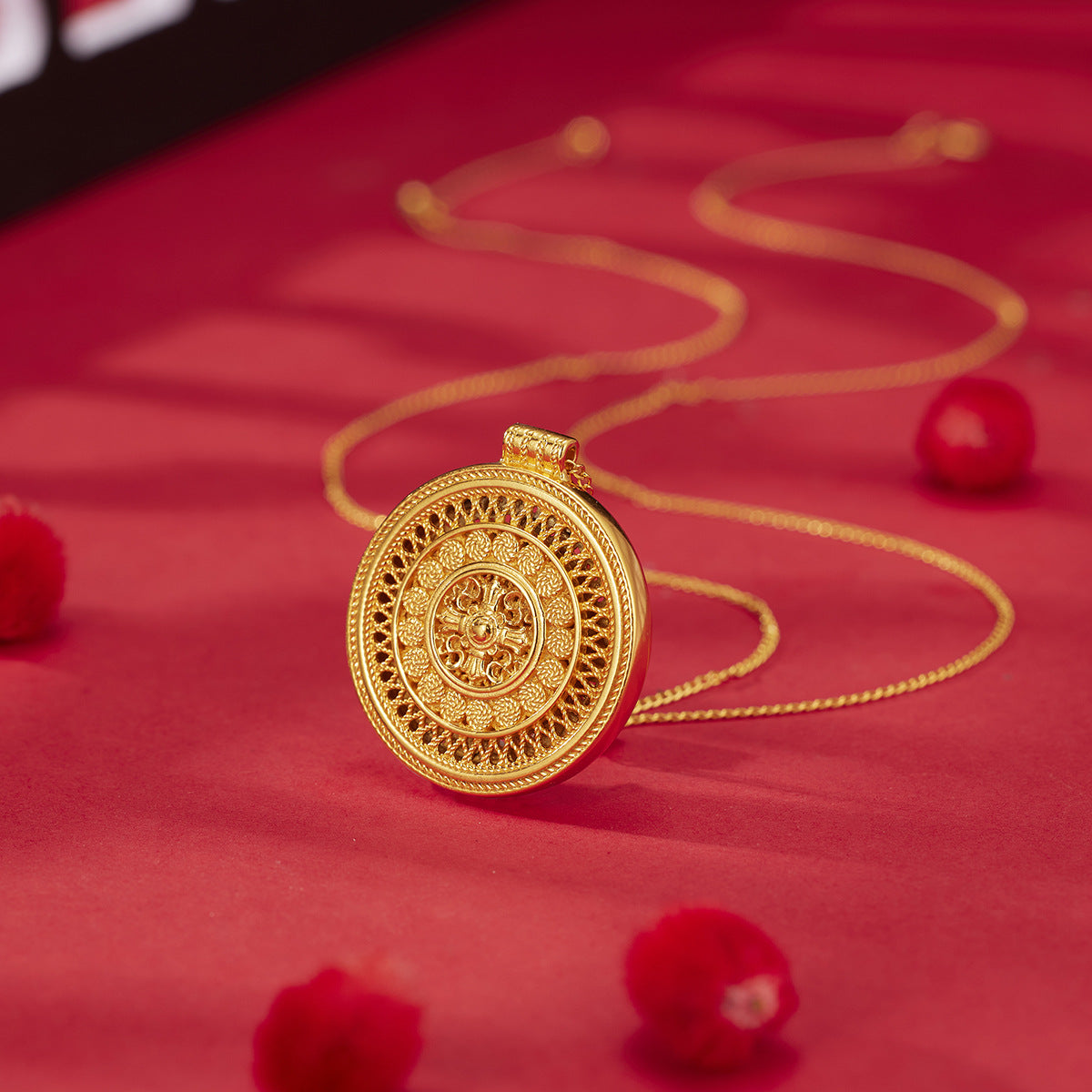 Gold necklace with a decorative pendant on a red background