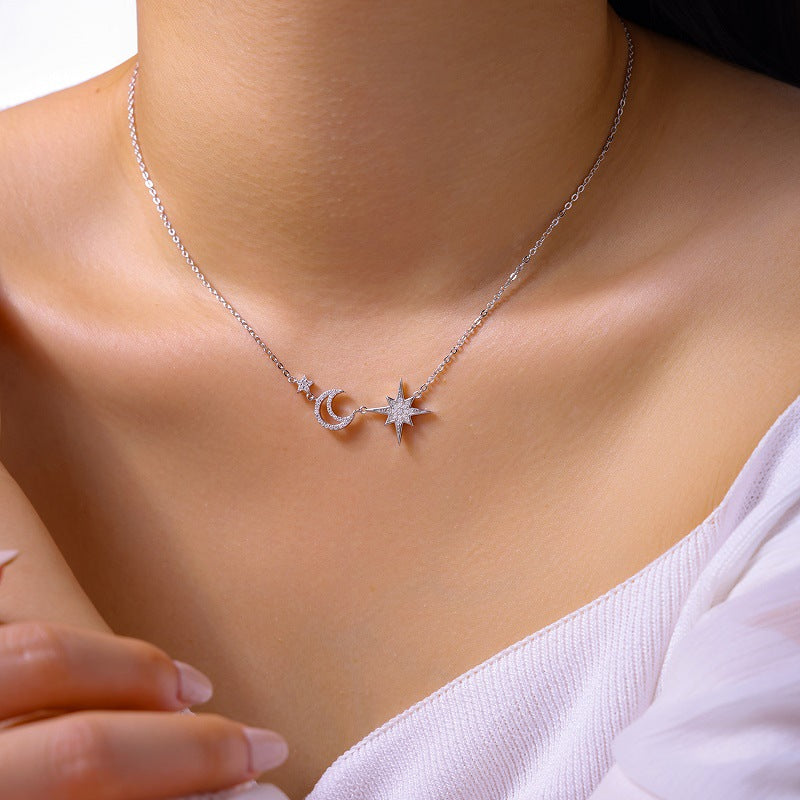 Necklace with star and moon pendant on a person wearing a white top.