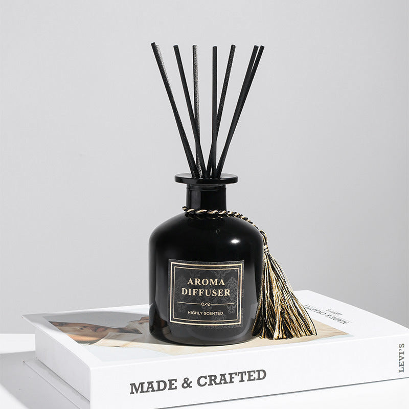 Black aroma diffuser with tassel on a white surface with a light gray background