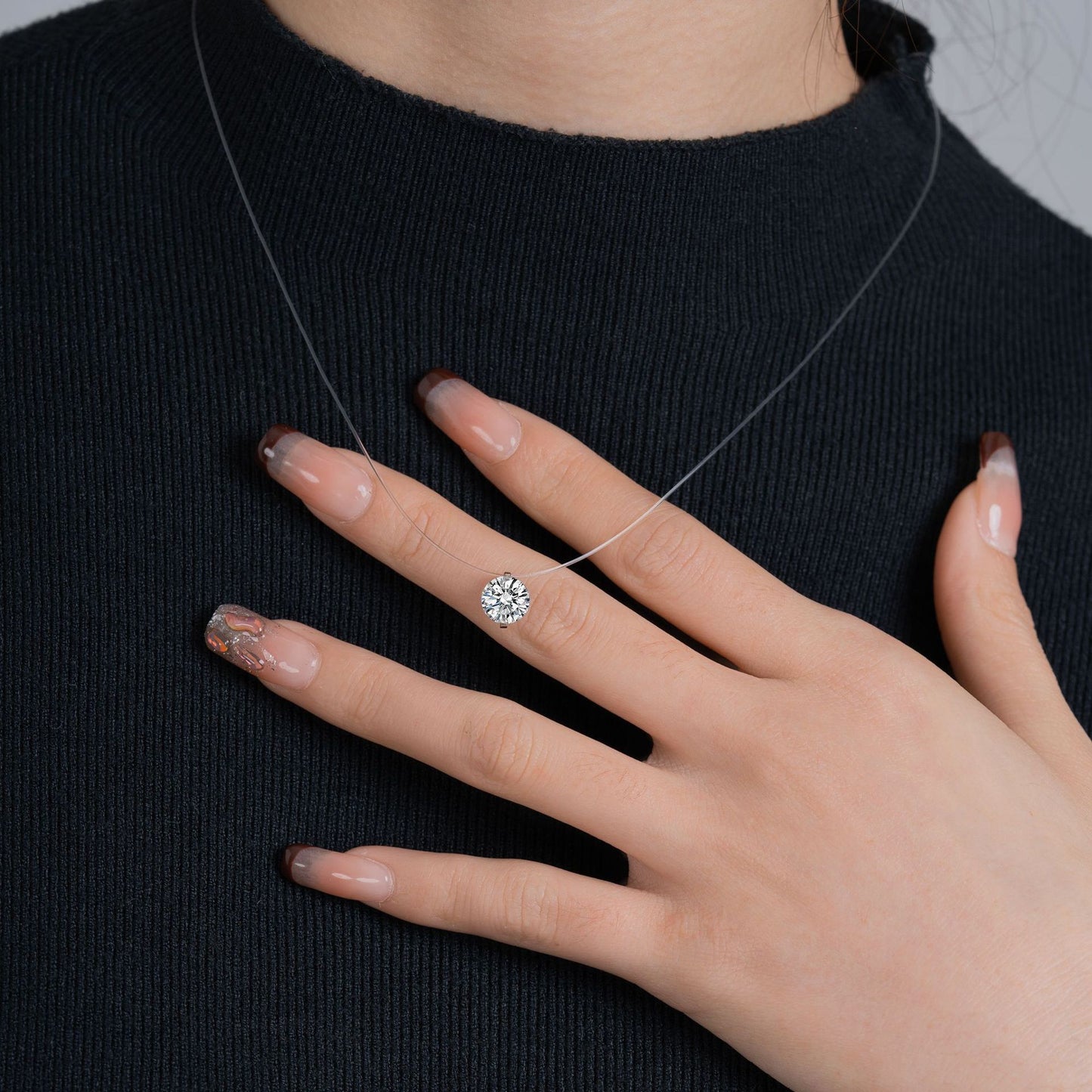 Hand wearing a diamond ring on a black background