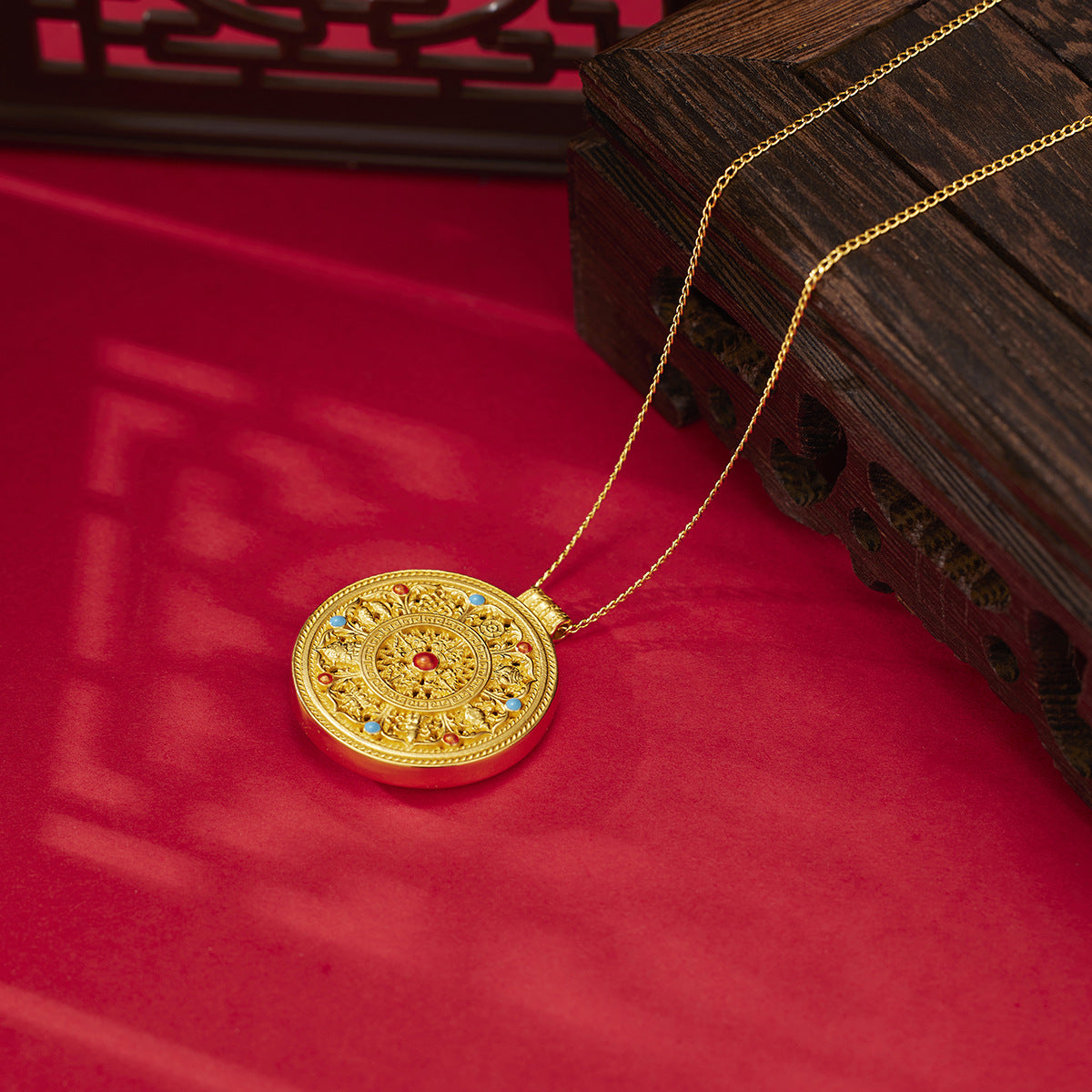 Gold necklace with a decorative pendant on a red surface