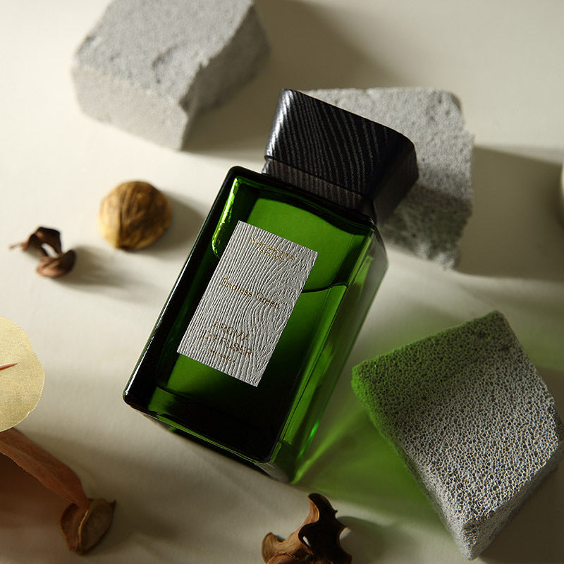 Green bottle with a label on a textured surface with rocks and nuts.