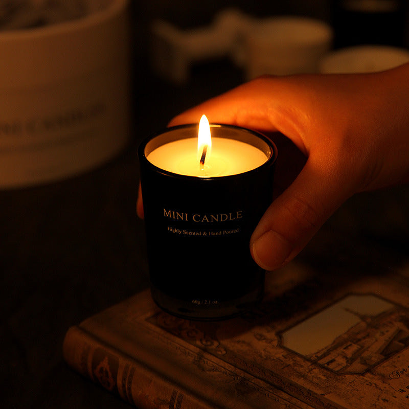 Hand holding a lit mini candle on an old book with a warm glow.
