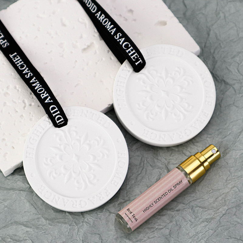 White aroma sachets with black text and a pink oil spray bottle on a gray surface
