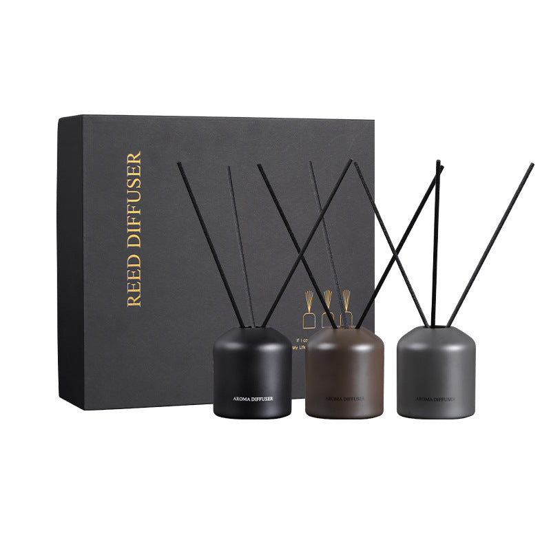 Reed diffuser set with three black containers and black sticks on a white background