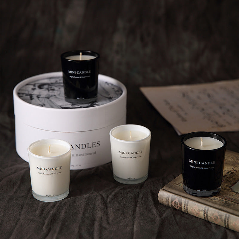 Mini candles in black and white containers on a dark surface with a blurred background