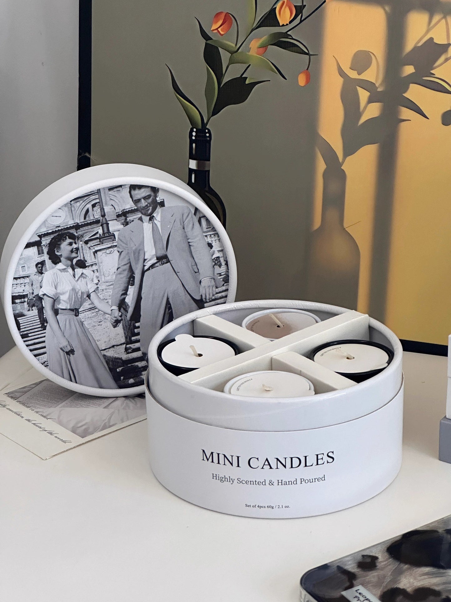 Set of mini candles in a round container with a vintage photo and decorative items in the background.