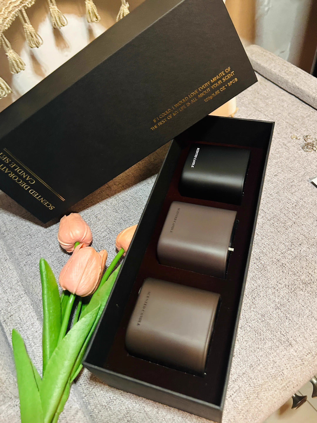 Two gray cylindrical objects in a black box with 'Ceramic Studio' branding, accompanied by pink tulips.