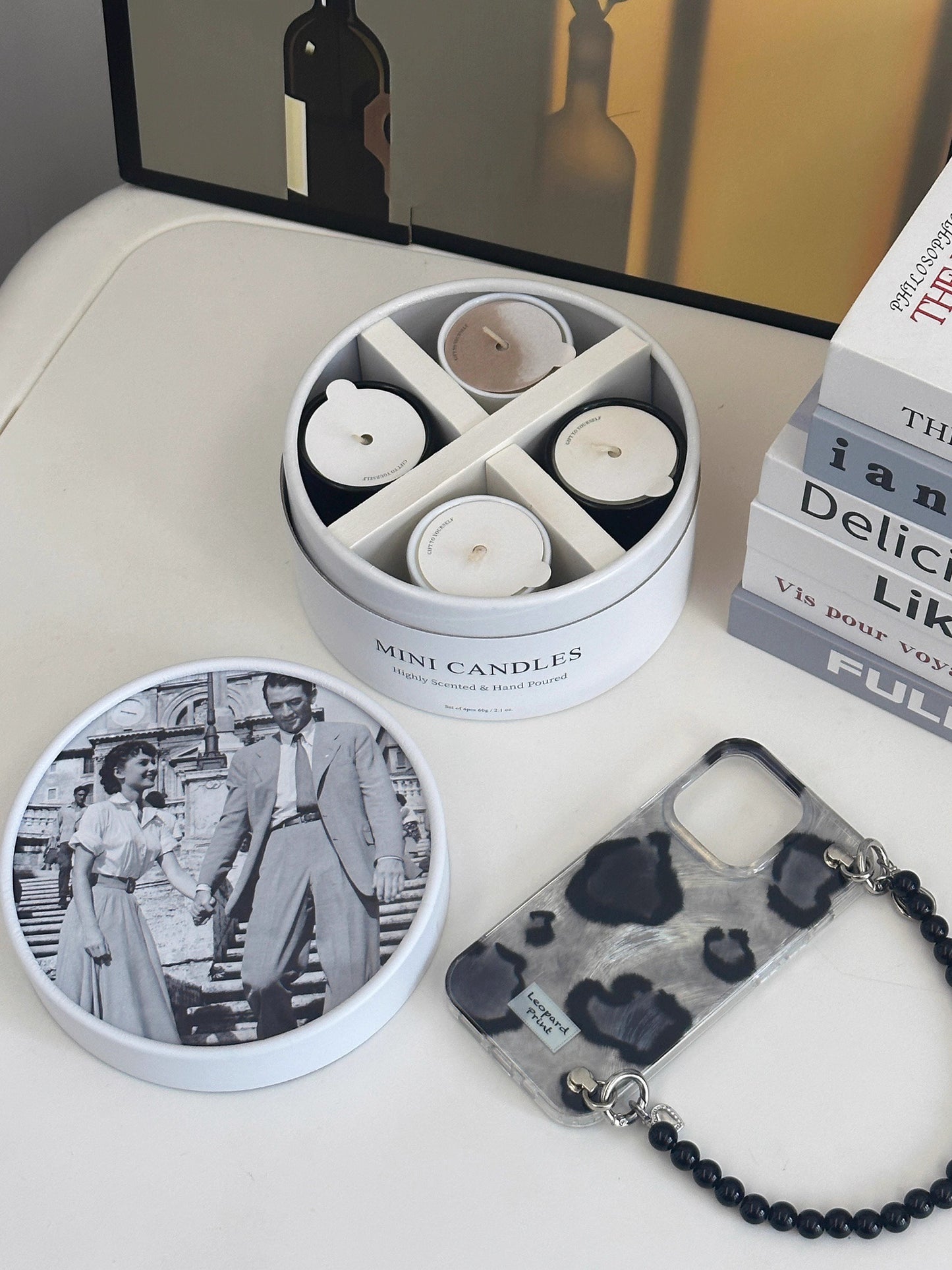 Set of mini candles in a tin with a keychain and photo album on a table.