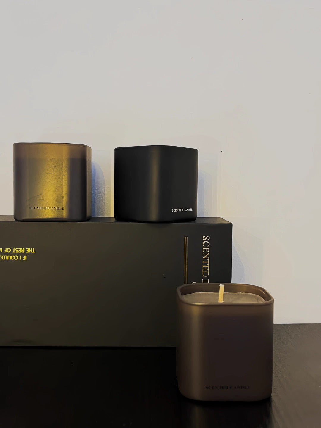 Three candles of different sizes on a dark surface with a plain background