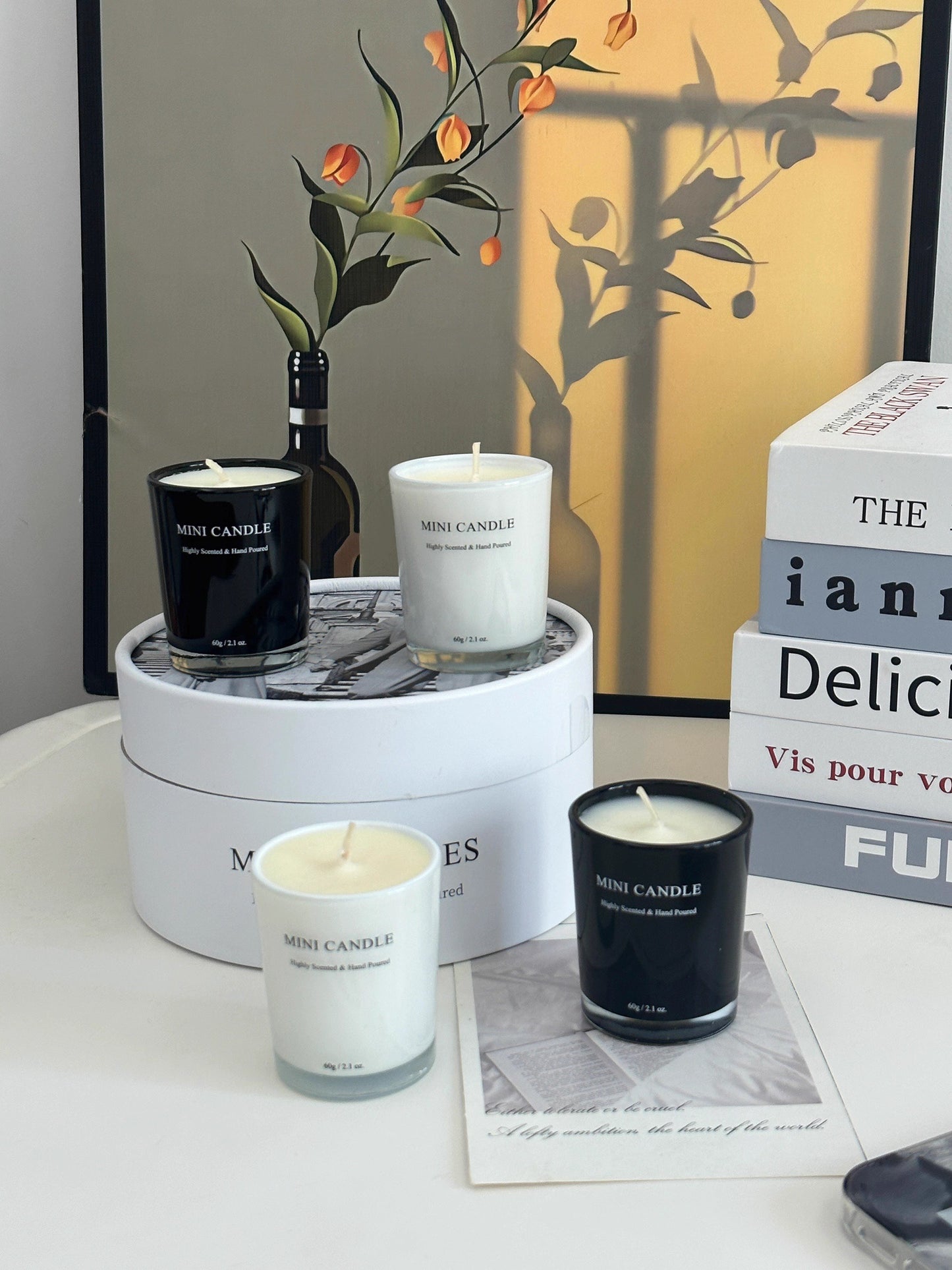 Three candles on a white surface with a decorative box and plant in the background.