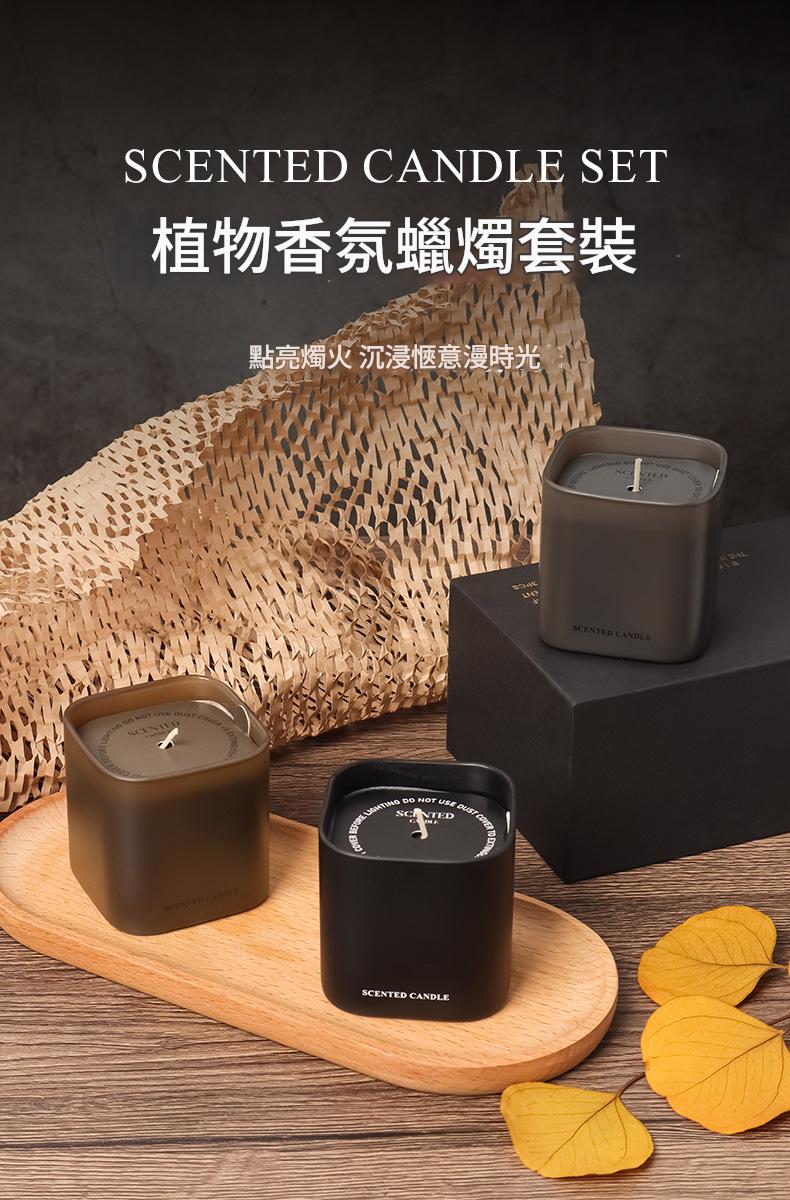 Scented candle set with three candles on a wooden tray, surrounded by leaves and a woven mat.
