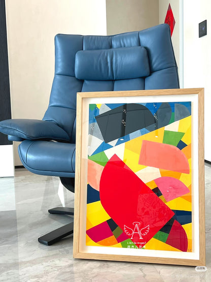 Colorful abstract art print in a wooden frame on a floor next to a blue chair.