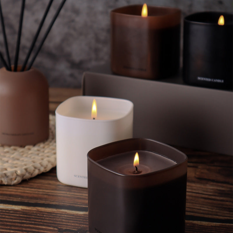 Candles in various containers on a wooden surface with a blurred background