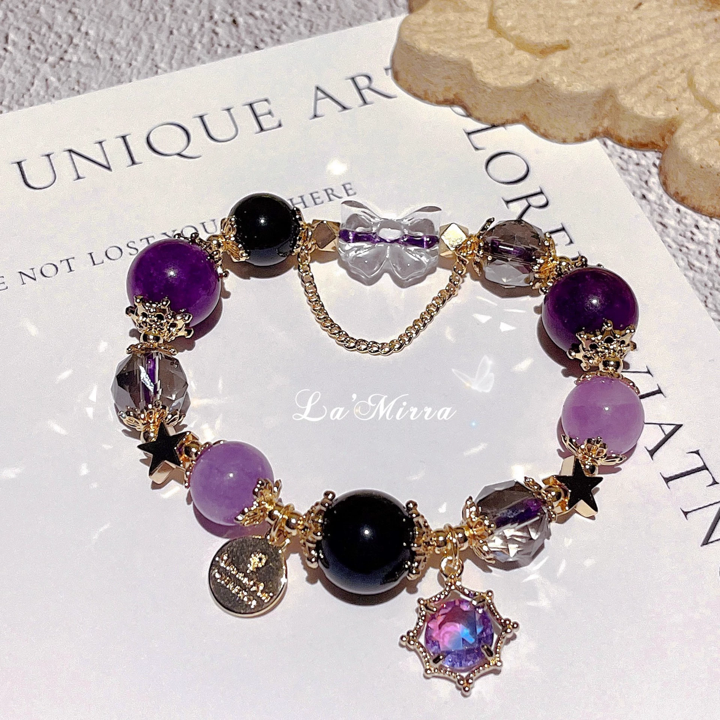 Purple beaded bracelet with gold accents on a textured surface