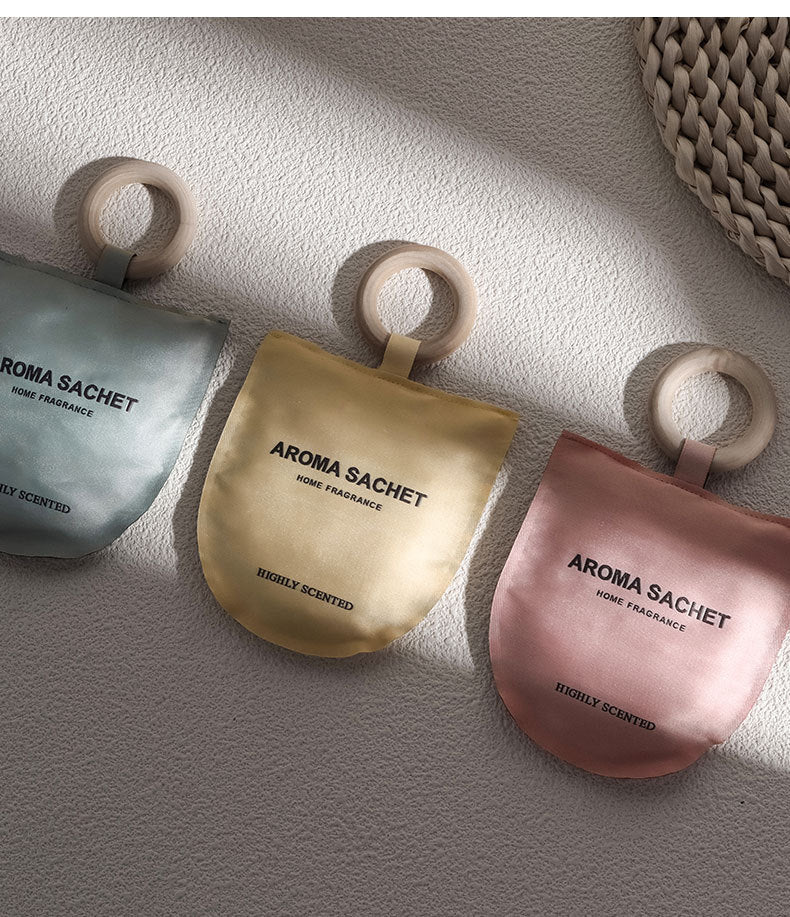 Three aroma sachets with wooden rings on a textured surface