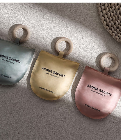 Three aroma sachets with wooden rings on a textured surface