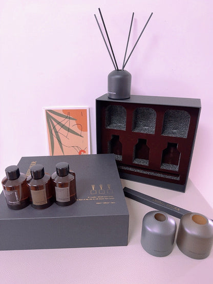 Set of diffusers including bottles, a diffuser stick, and a box on a light pink background