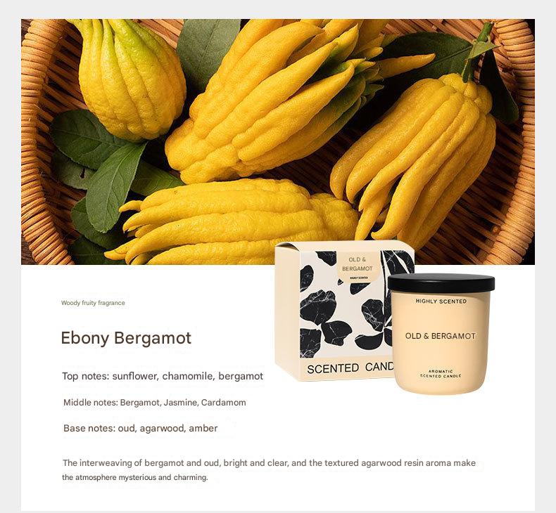 Candle with packaging labeled 'Old & Bergamot' and a basket of yellow fruits on a white background.