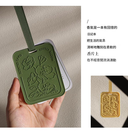 Green floral embossed tag held by a hand with text on a beige background