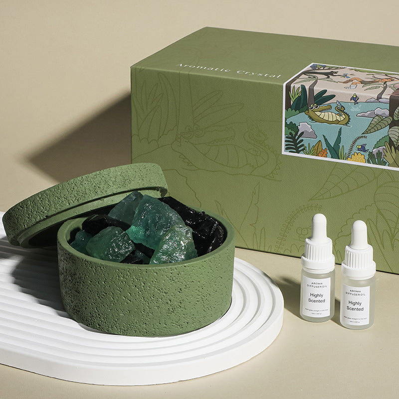 Green container with crystals, a green box with illustrations, and two bottles labeled 'Highly Scented' on a beige background.