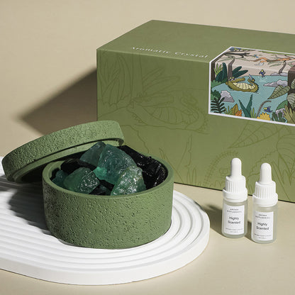 Green container with crystals, a green box with illustrations, and two bottles labeled 'Highly Scented' on a beige background.