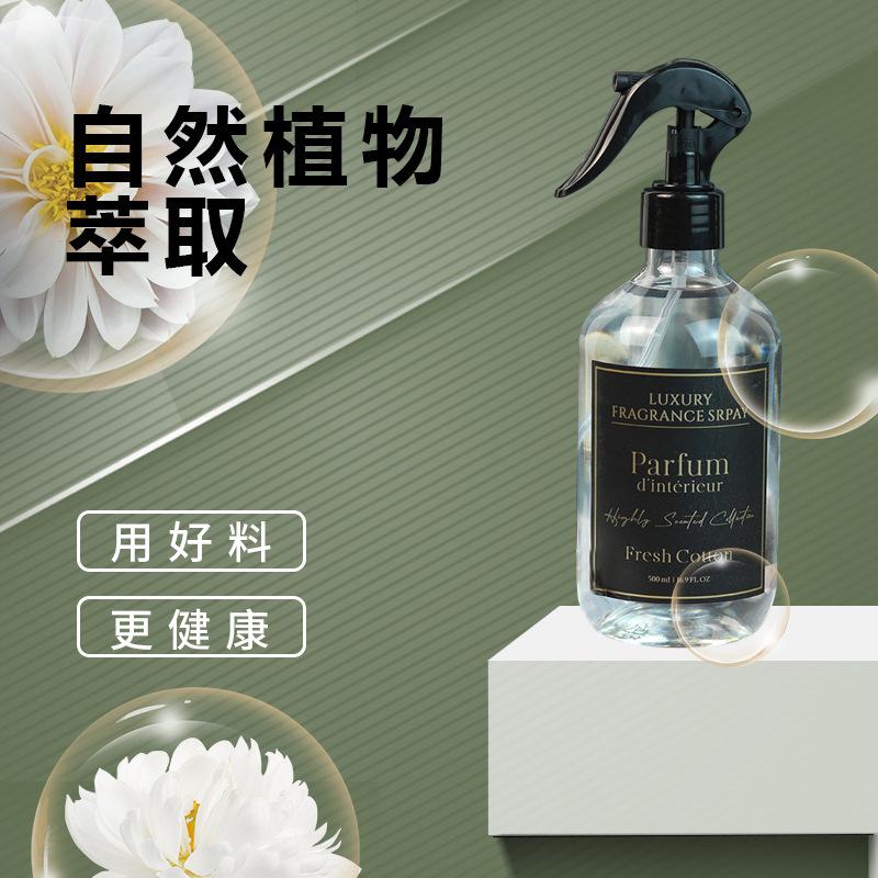 Spray bottle labeled 'Parfum d'Intérieur' on a white platform with green background and floral elements.