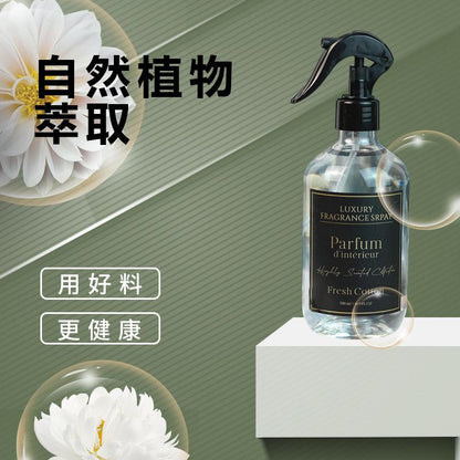 Spray bottle labeled 'Parfum d'Intérieur' on a white platform with green background and floral elements.