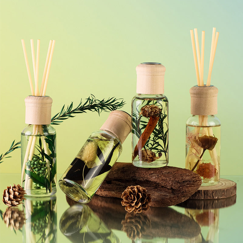 Set of diffuser bottles with natural elements on a reflective surface with a green gradient background