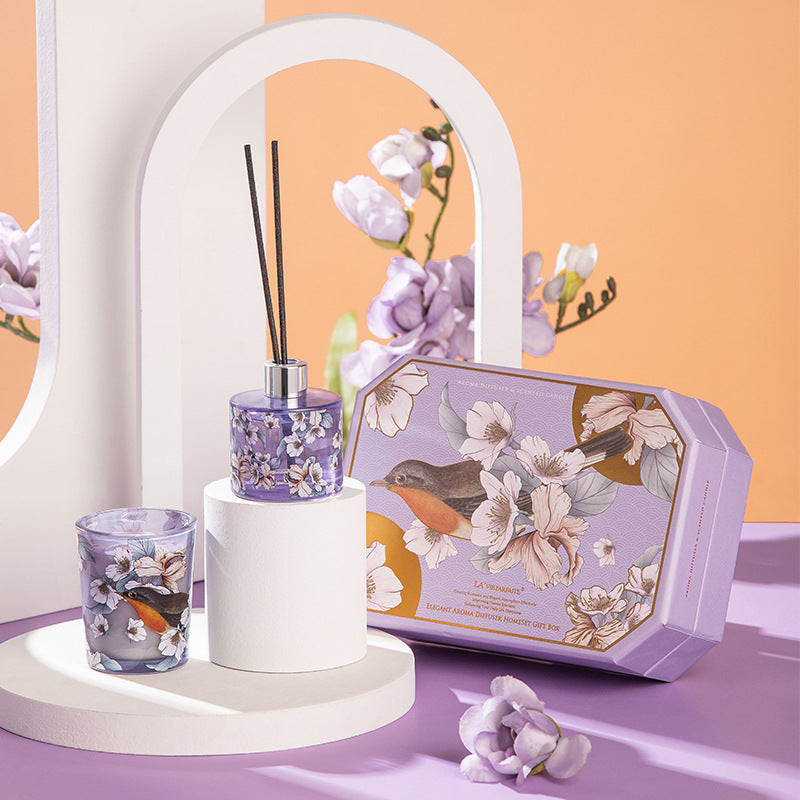 Decorative set with diffuser, glass, and floral packaging on a pastel background