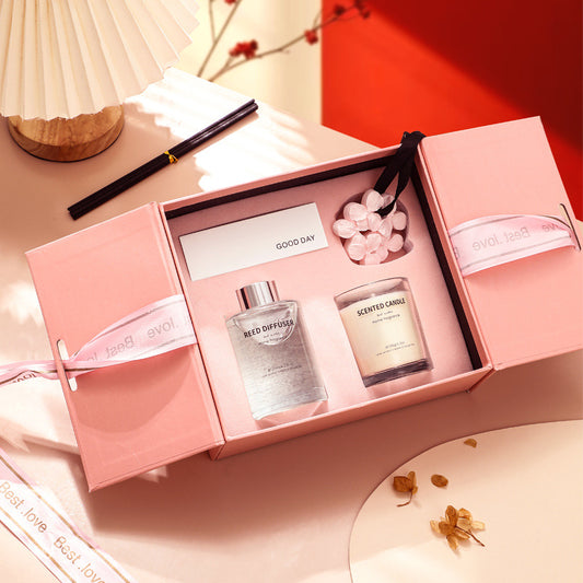 Pink gift box with diffuser, candle, and stationery on a soft pink background