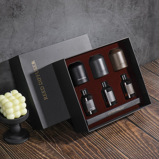 Set of Reed Diffuser products in a box on a wooden surface with a gray background