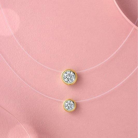 Gold earrings with clear gemstones on a pink background