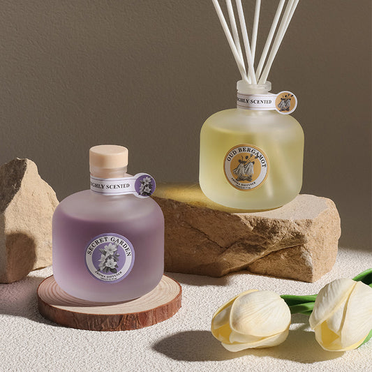 Two diffusers, one purple and one clear with a label, on a neutral background.