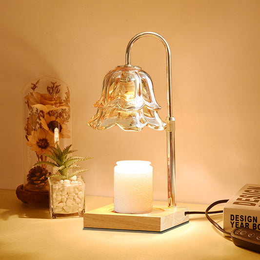 Decorative table lamp with glass shade on a wooden base, surrounded by books and a small plant.