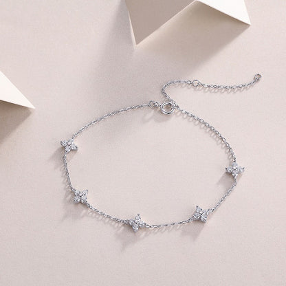 Silver bracelet with star-shaped charms on a light pink background