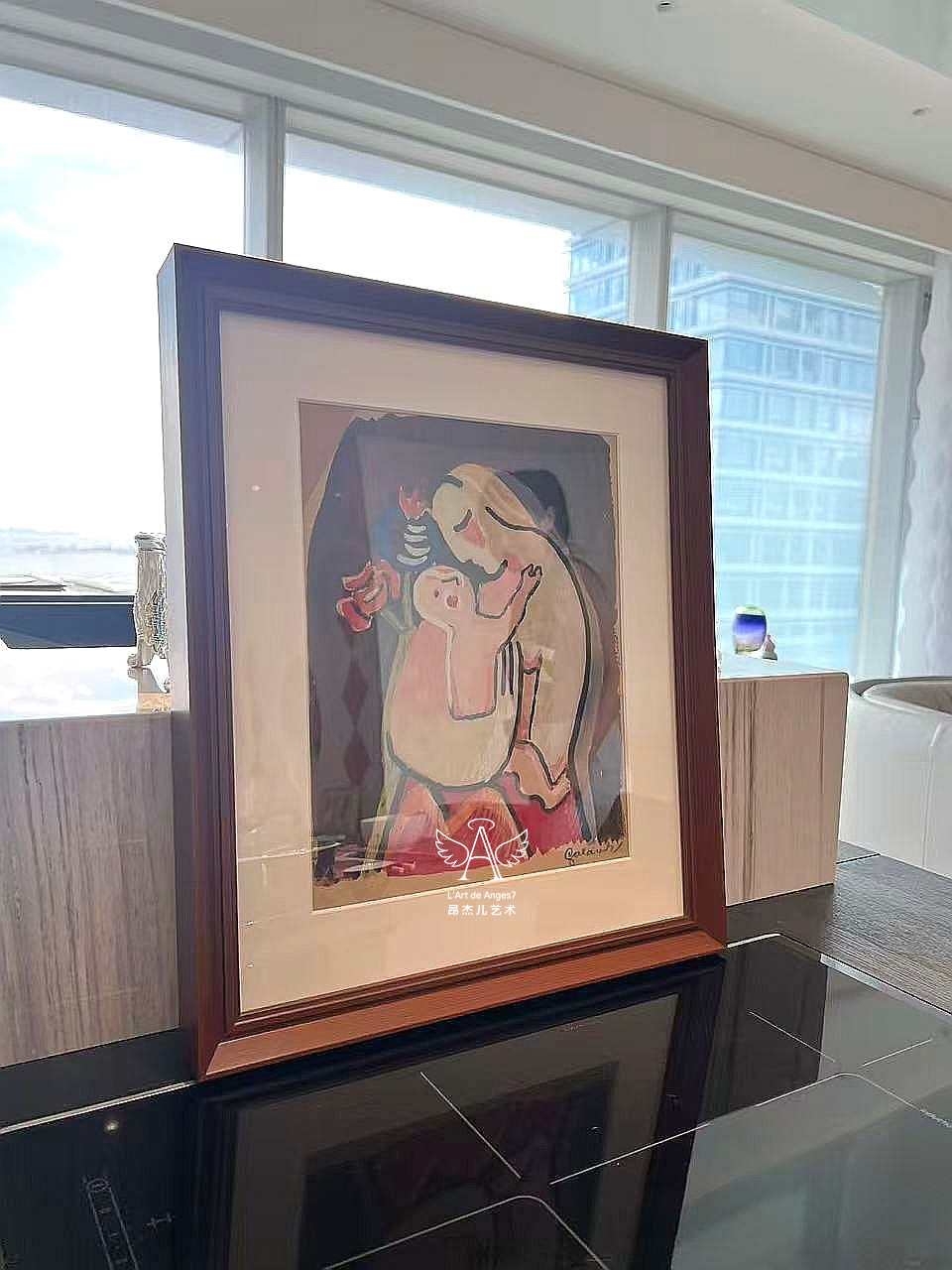 Framed artwork on a reflective surface with a cityscape in the background