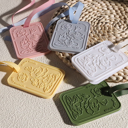 Five floral-patterned luggage tags in different colors on a woven surface.