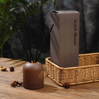 Scent Bloom diffuser and packaging on a wooden surface with plants in the background